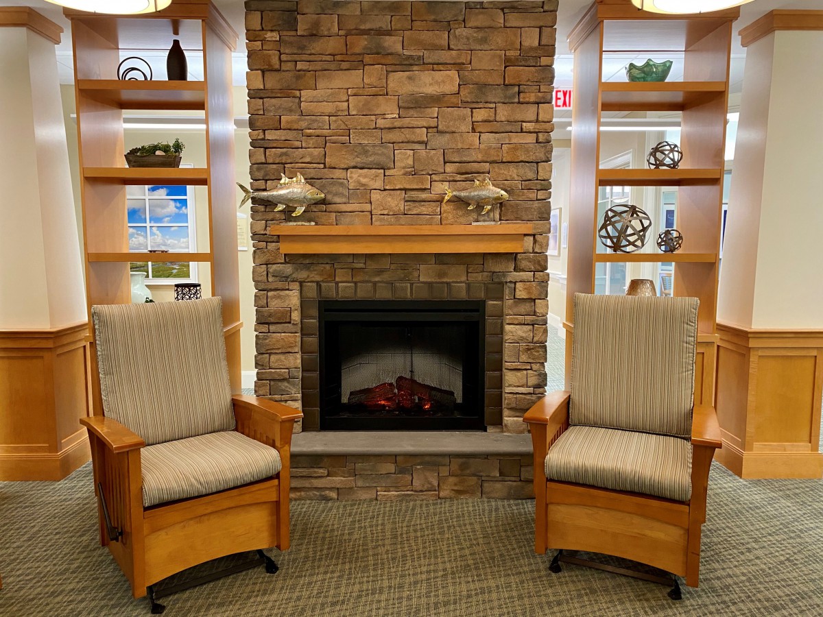 A cozy living room setting with two chairs in front of a brick fireplace and built-in shelves.