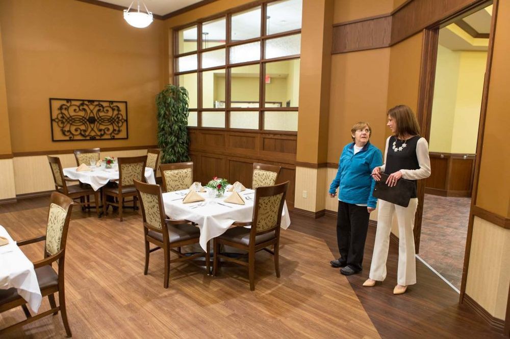 Two people conversing in a well-lit dining area with set tables.