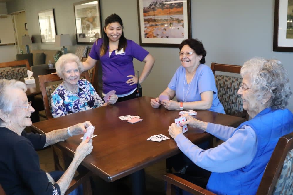 Seniors enjoying a card game with a caregiver at a nursing home.