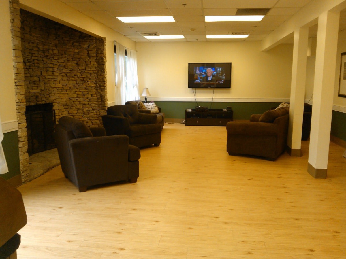 A cozy living room with sofas, a fireplace, and a television on the wall.