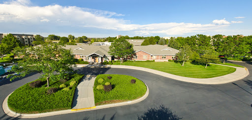 Aerial view of a residential building surrounded by lush greenery and a winding road.