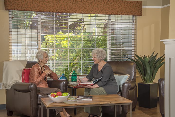 Two elderly women engaging in a conversation while seated in a cozy living room.