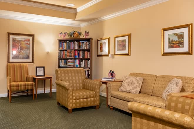 A cozy living room featuring comfortable armchairs, a sofa, and a well-stocked bookshelf.