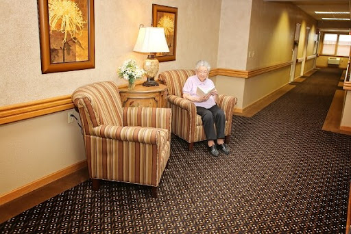A cozy waiting area featuring striped chairs and a lamp, with a senior citizen reading in the corner.