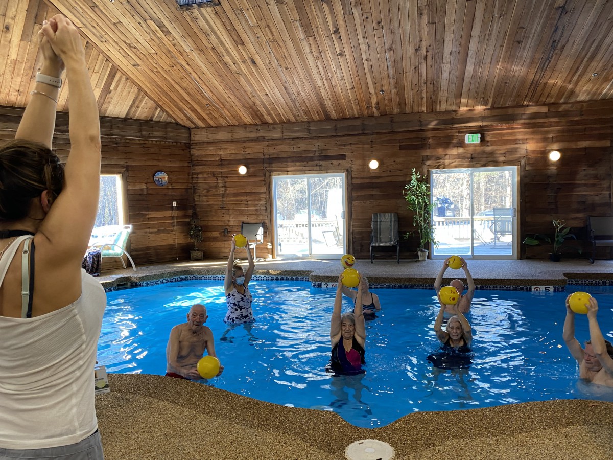 A group of people participating in a water aerobics class in an indoor pool.