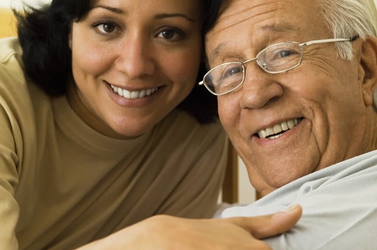 A smiling woman and an elderly man enjoying a moment together indoors.
