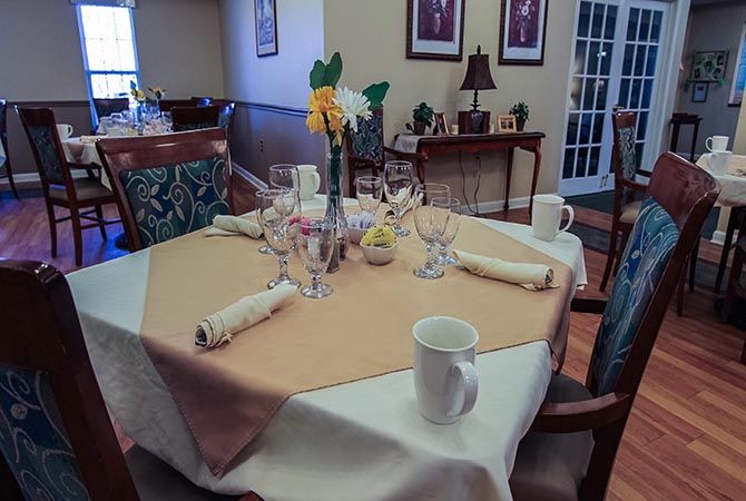 A dining table set for a meal with neatly arranged tableware and a floral centerpiece.