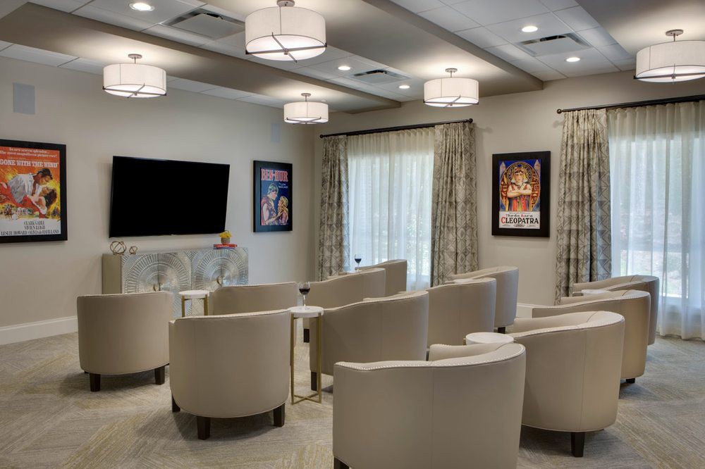 A modern conference room with comfortable chairs and a large television screen, decorated with framed artwork on the walls.