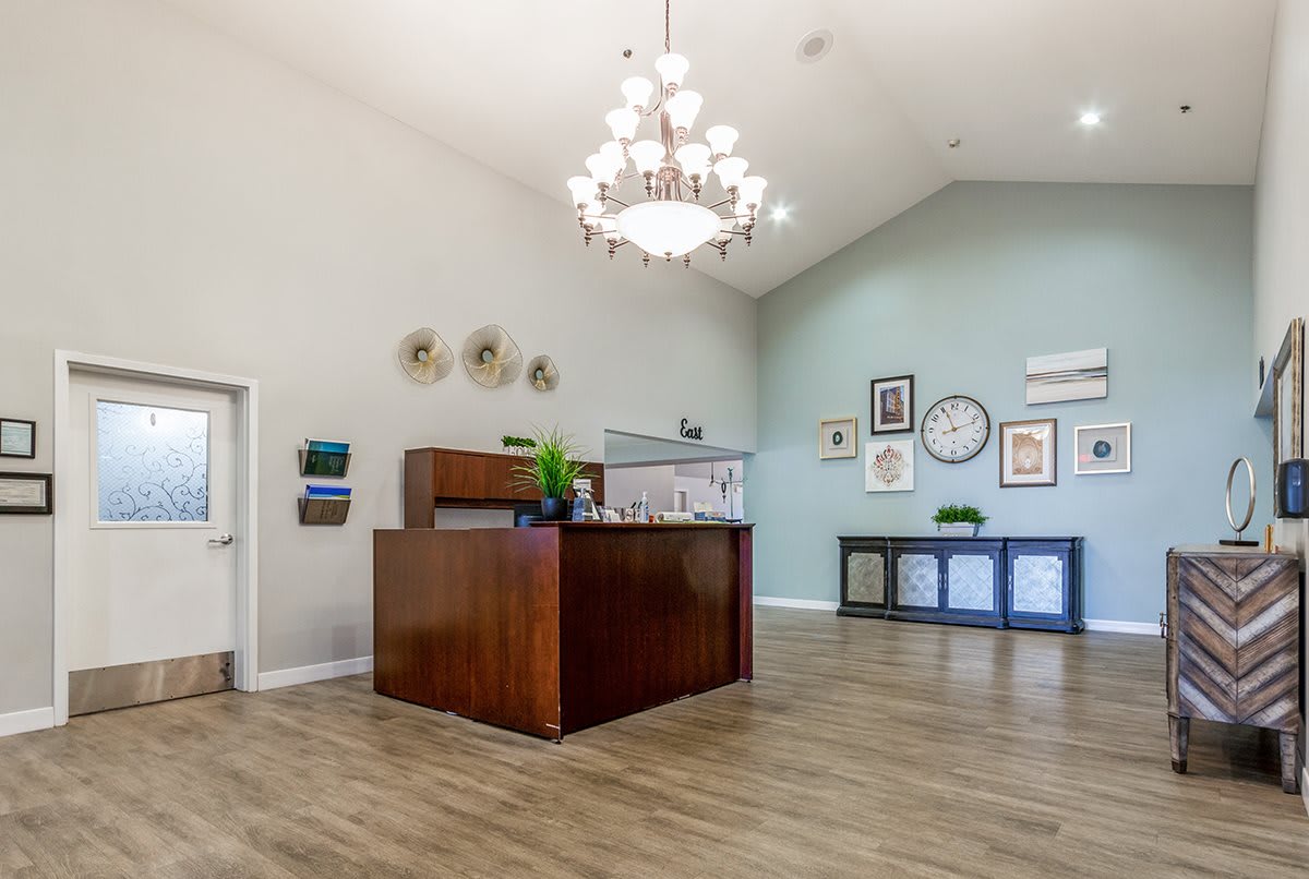 A modern office reception area with a chandelier and decorative wall art.