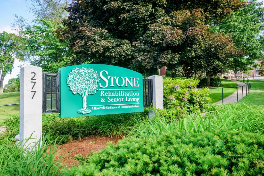 Entrance sign for Stone Rehabilitation and Senior Living surrounded by greenery.
