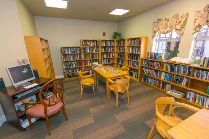 A cozy library reading area with bookshelves, seating, and a central table.