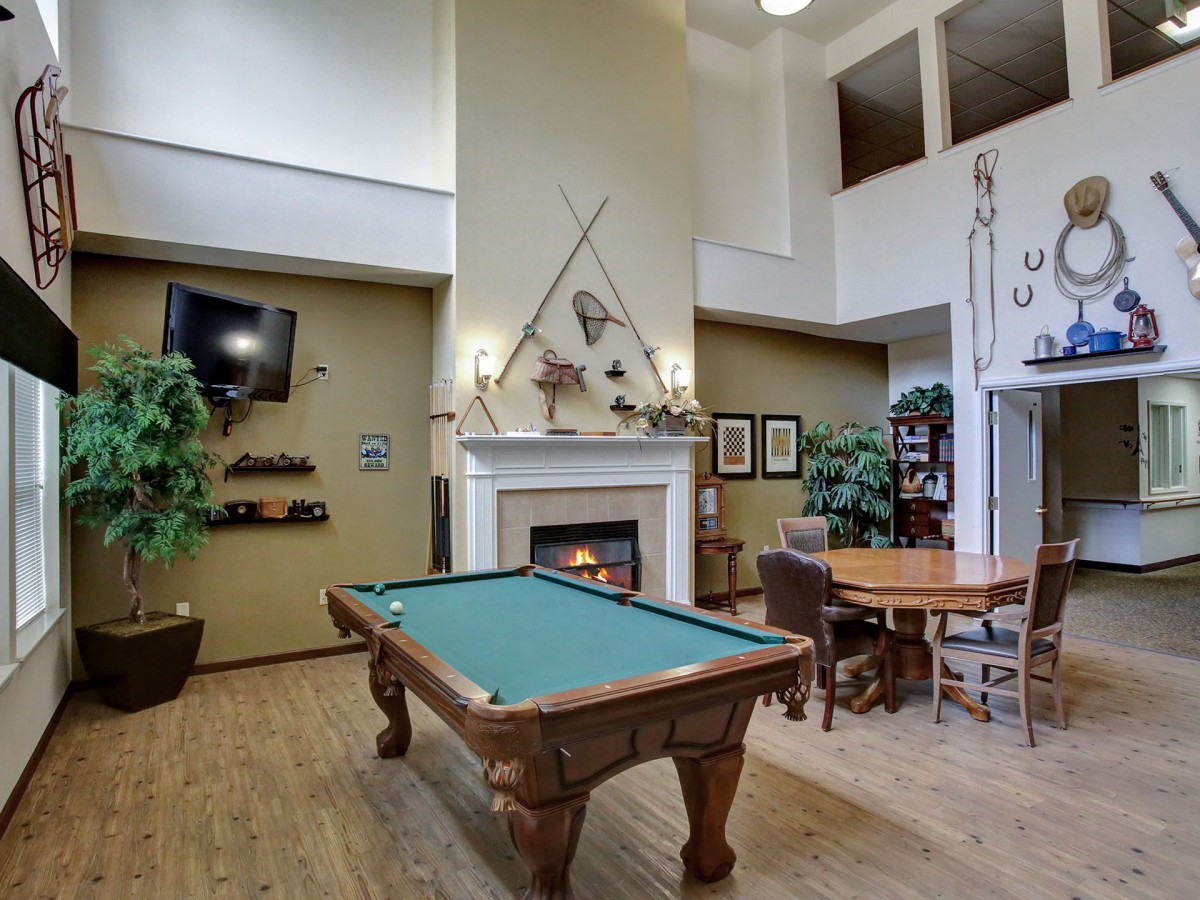 A cozy game room featuring a pool table, fireplace, and comfortable seating.