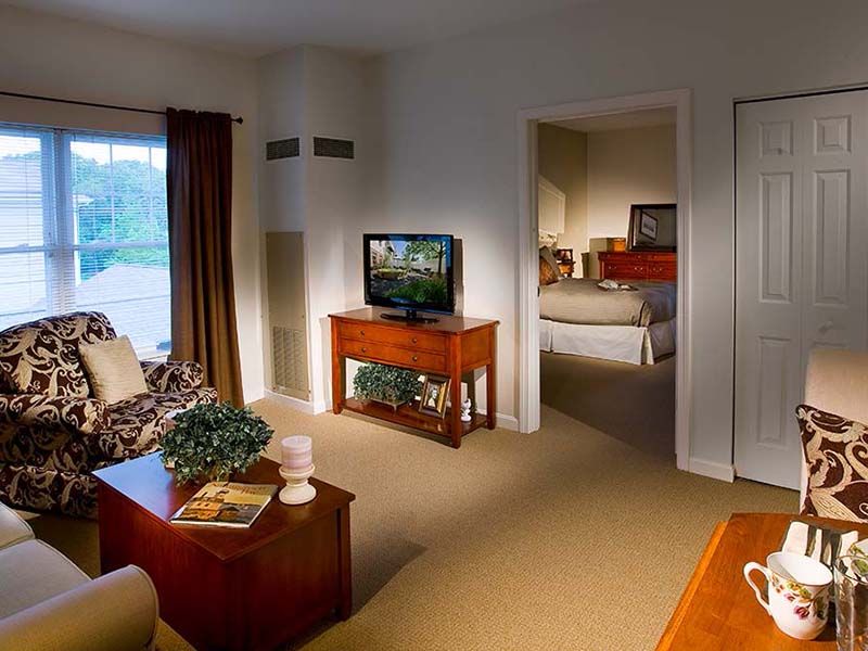 A cozy living room with a view into the bedroom, featuring a television and comfortable furnishings.