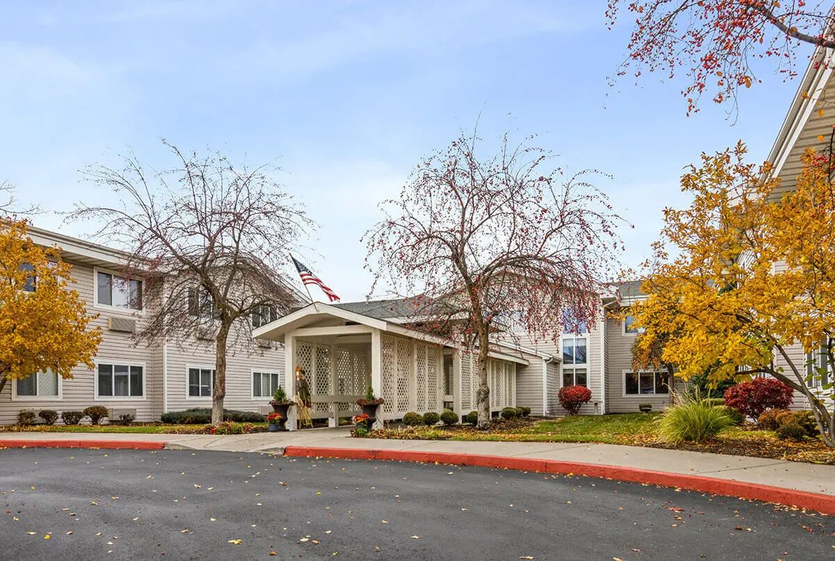 A building with a prominent entrance, surrounded by autumn trees and a circular driveway.