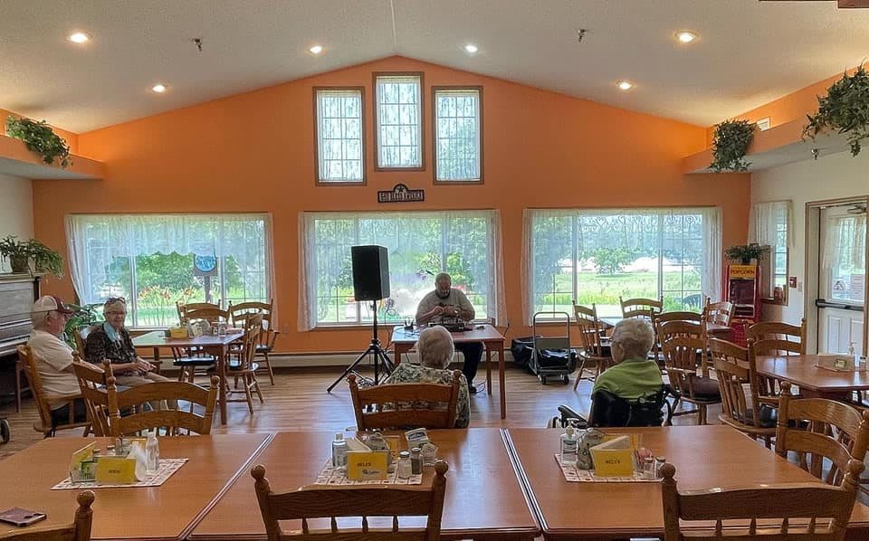 A small gathering in a dining area with orange walls and large windows.