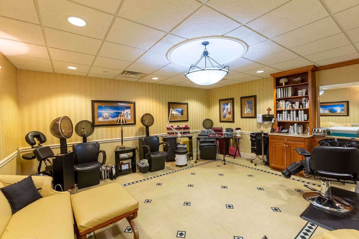 A well-furnished salon interior featuring multiple hair styling stations, comfortable chairs, and decorative artwork on the walls.
