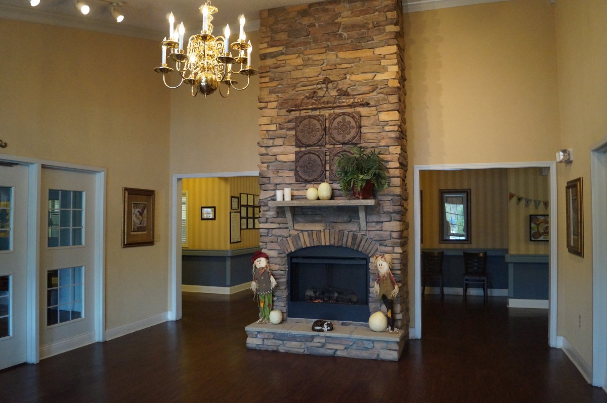 A cozy living room with a stone fireplace and elegant chandelier.