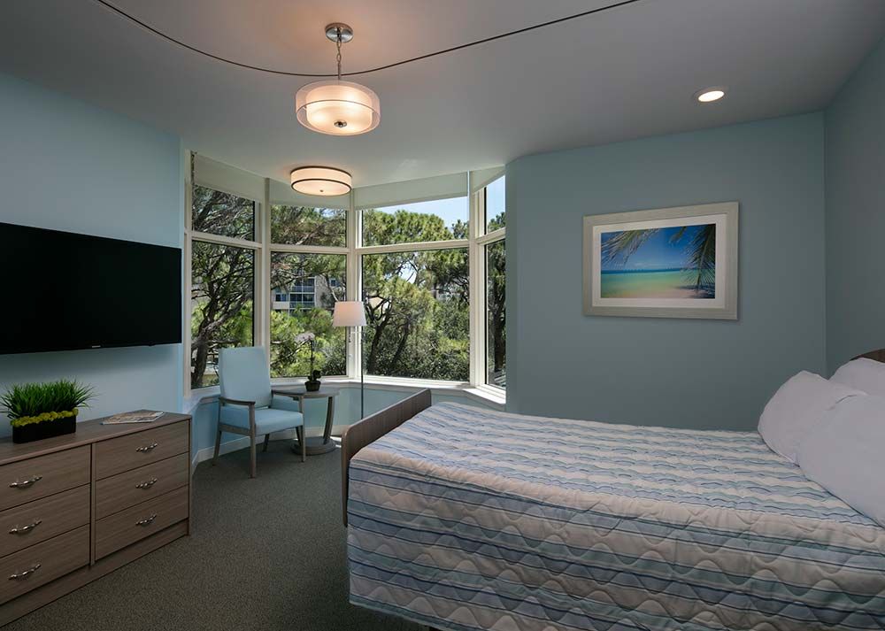 A modern bedroom featuring a large window with natural light, contemporary furniture, and tasteful decor.