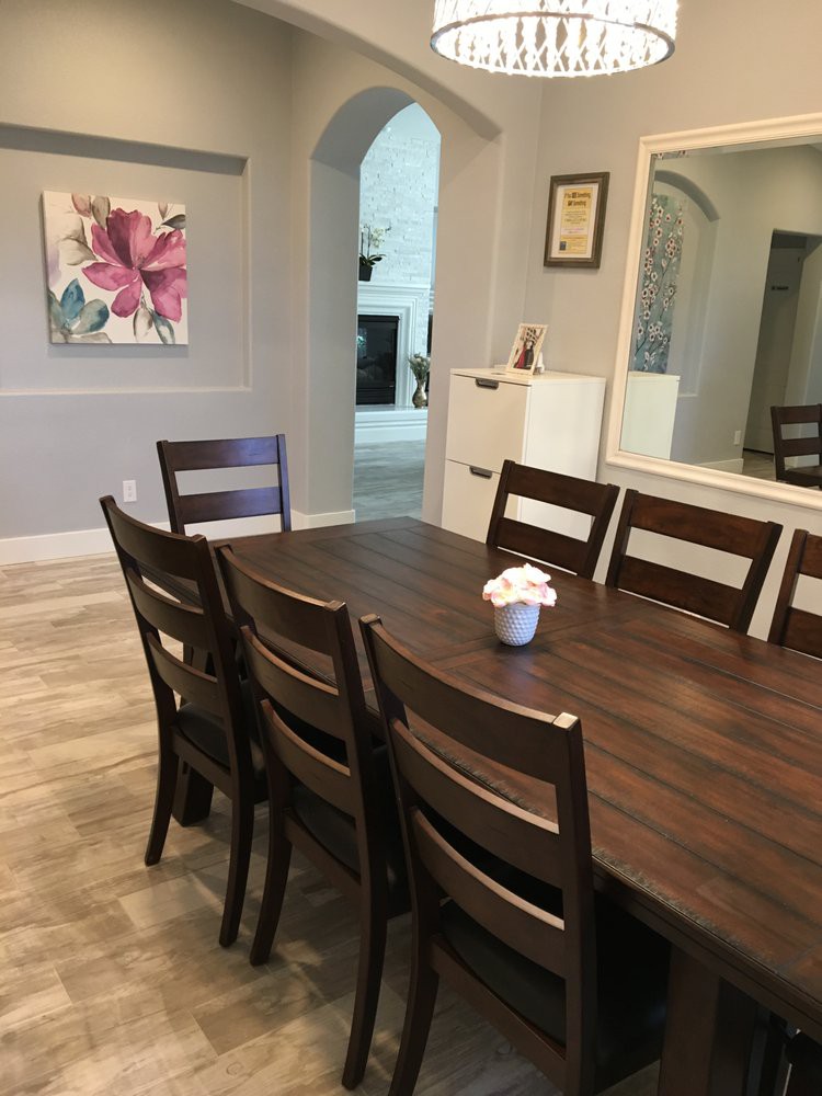A modern dining room with a dark wooden table and chairs, adorned with a small flower arrangement.