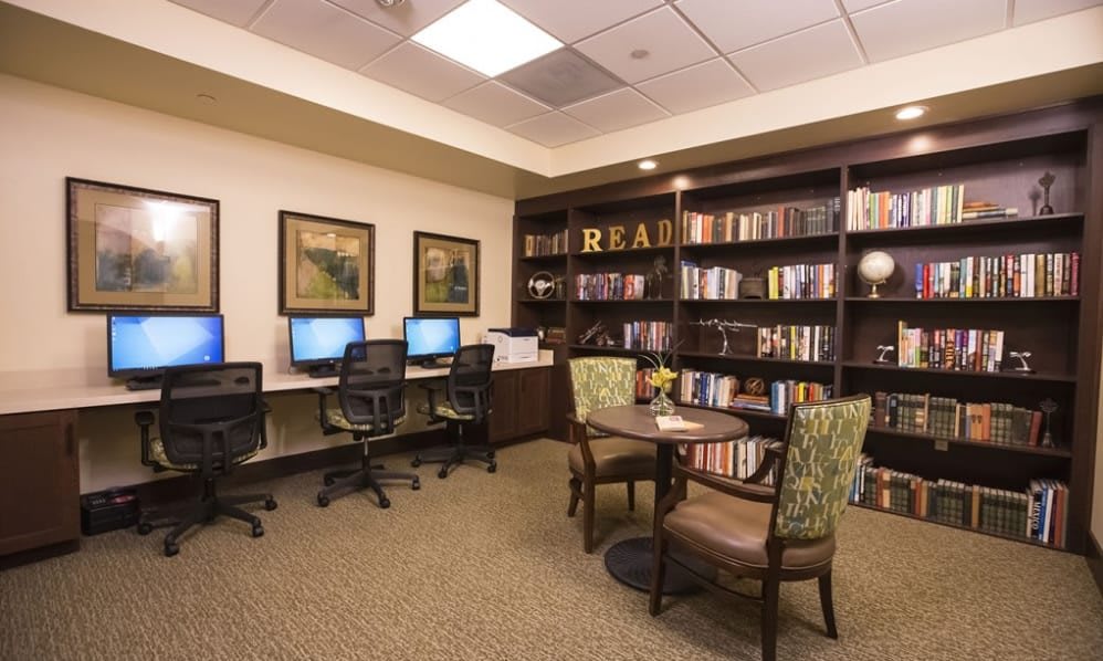A cozy library room with computers, bookshelves, and a reading area.