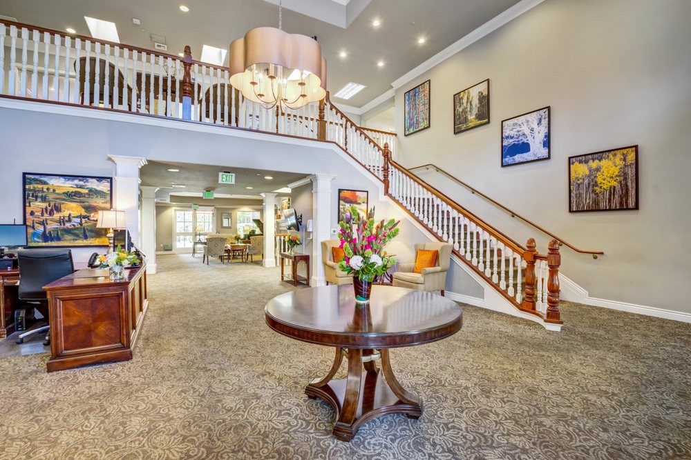 A spacious lobby with a grand staircase, elegant chandelier, and tasteful decor.