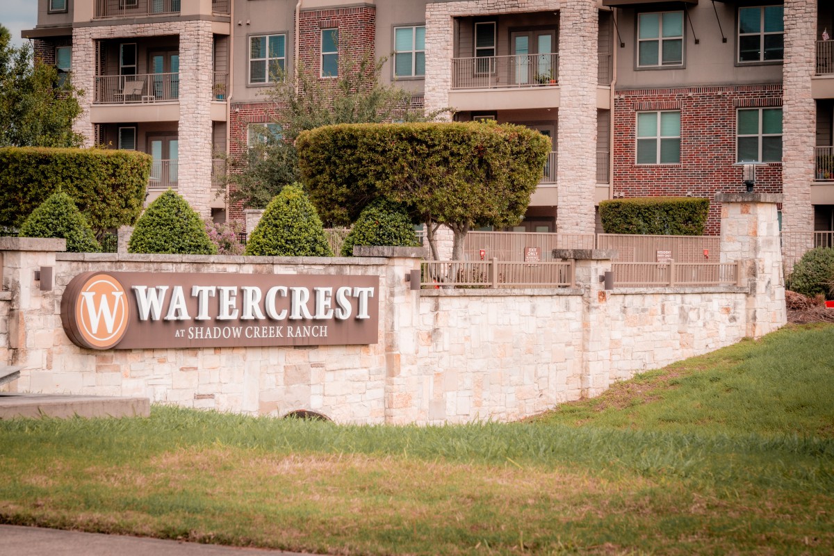 An apartment complex named Watercrest with neatly trimmed bushes and a well-maintained entrance.