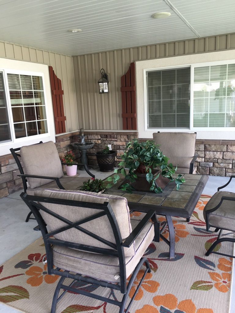 A cozy patio setup with comfortable chairs surrounding a table, adorned with a potted plant.