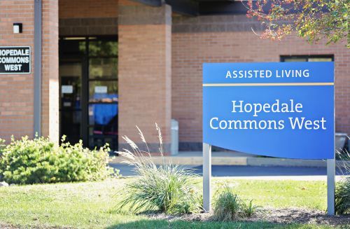 Entrance of Hopedale Commons Assisted Living facility with a sign in front.