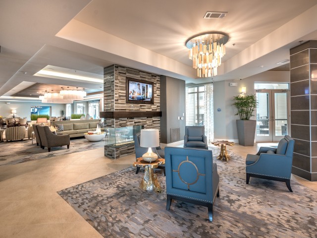 A luxurious and modern living room with elegant furnishings, featuring a chandelier, fireplace, and comfortable seating.