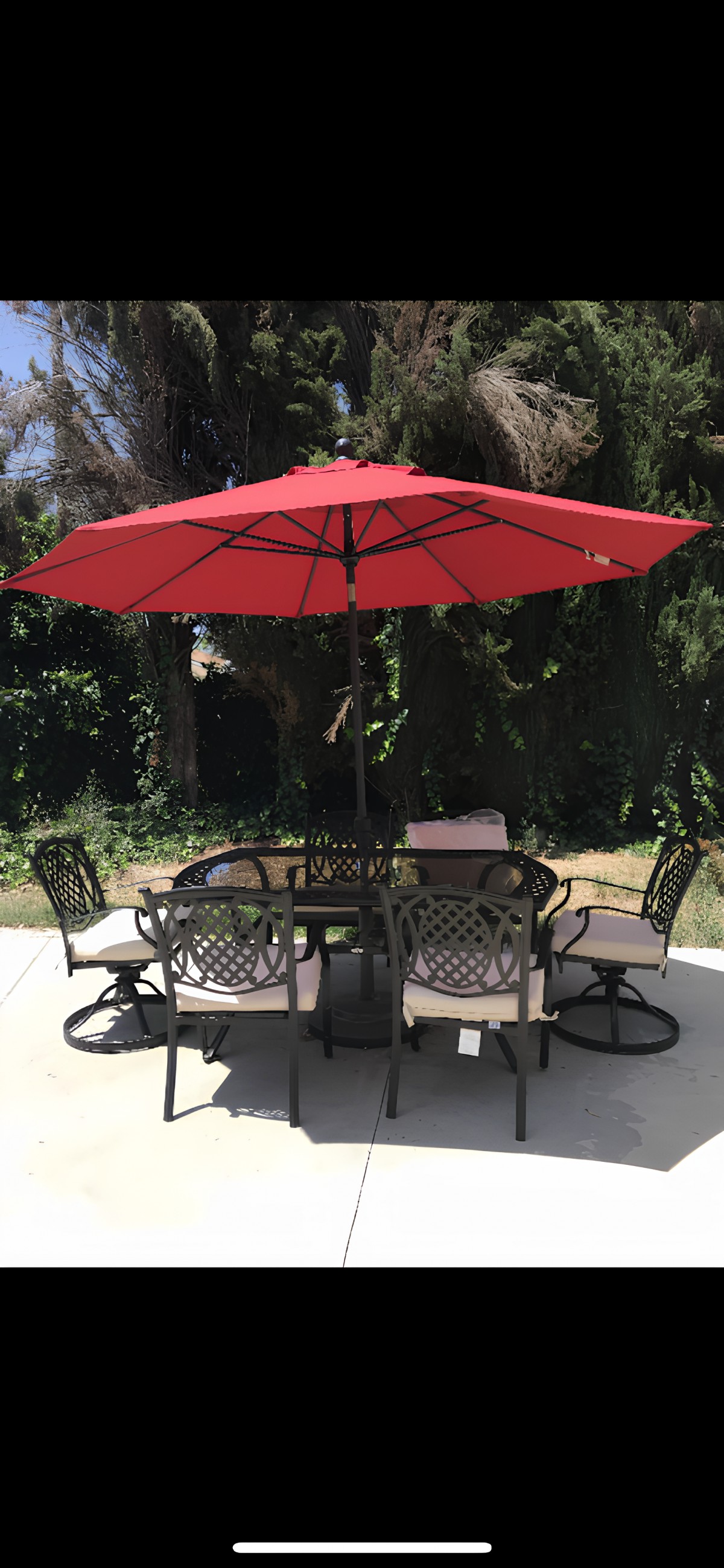 A patio set with a red umbrella and chairs in a garden setting.