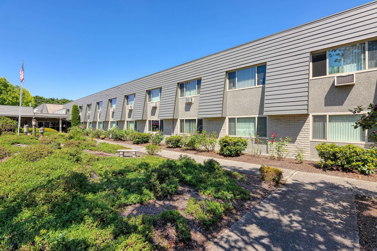 A modern building exterior with neatly landscaped surroundings under a clear blue sky.