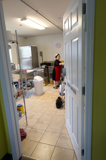 A glimpse into a busy kitchen where a woman is preparing food.