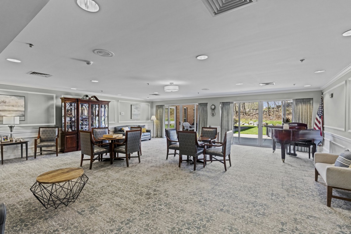 A spacious dining area with multiple tables and chairs, featuring large windows and a chandelier.