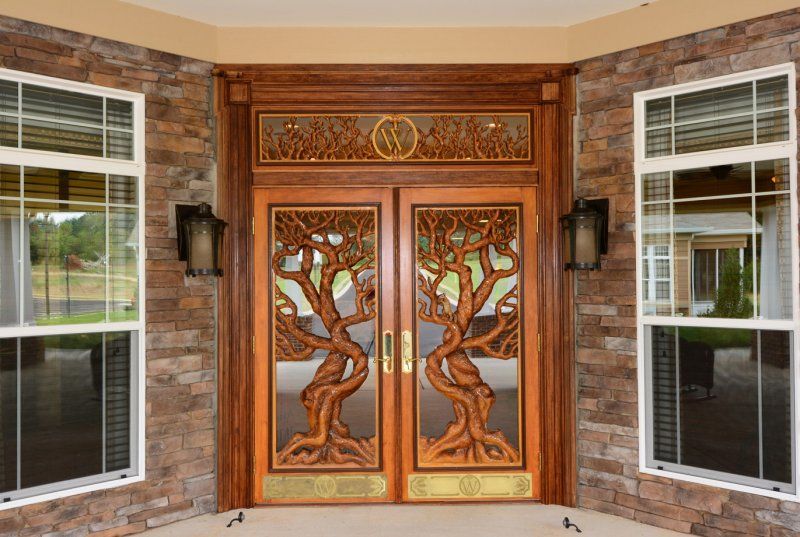 A beautifully crafted wooden front door with intricate tree carvings and glass inlays, providing an elegant entryway to a home.