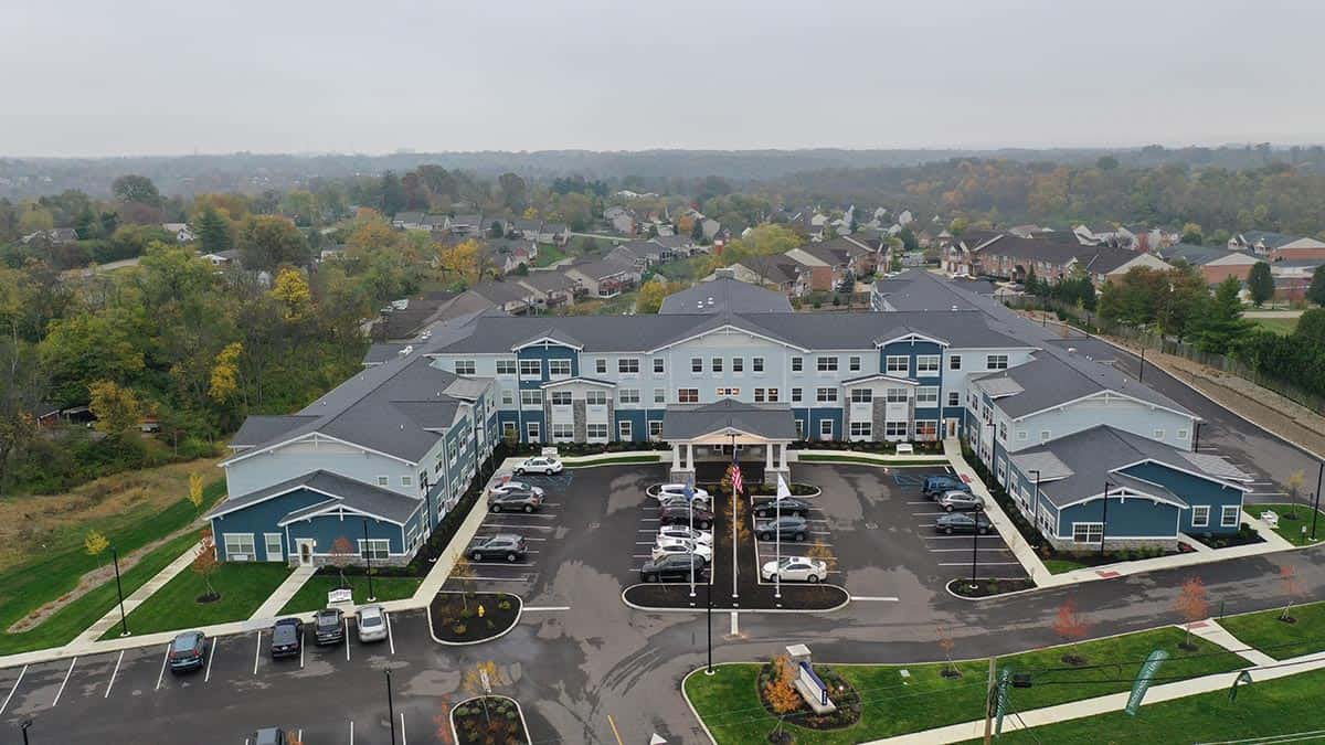 Aerial view of a large building with a surrounding parking lot in a suburban setting.
