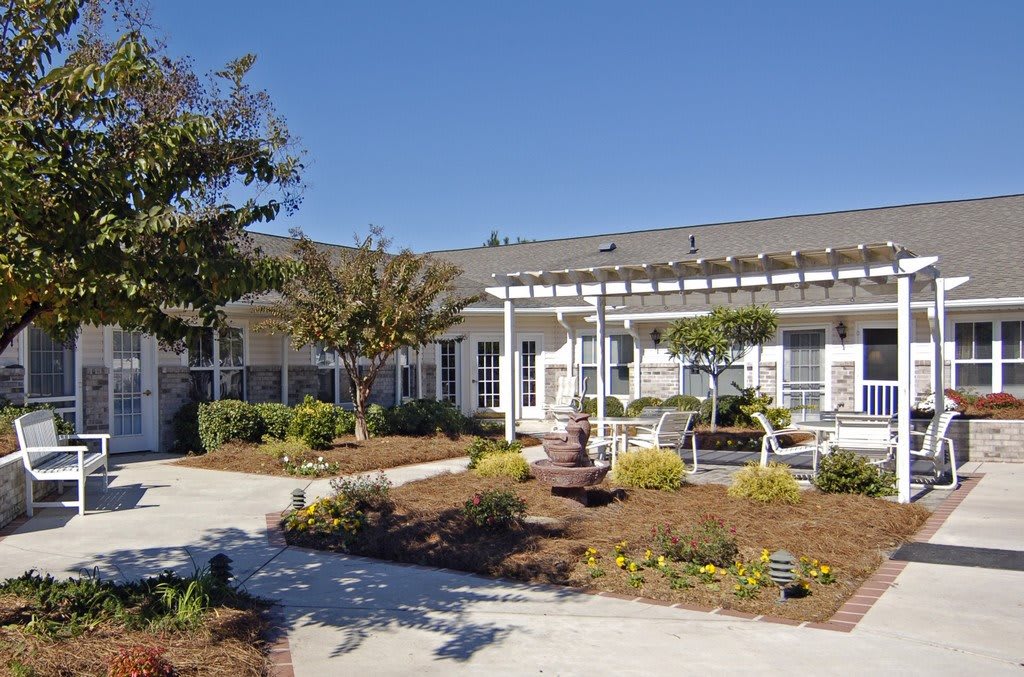 A well-maintained residential building with landscaped gardens and a clear blue sky.
