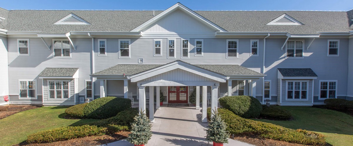 A front view of a residential building with a covered entrance and landscaped surroundings.
