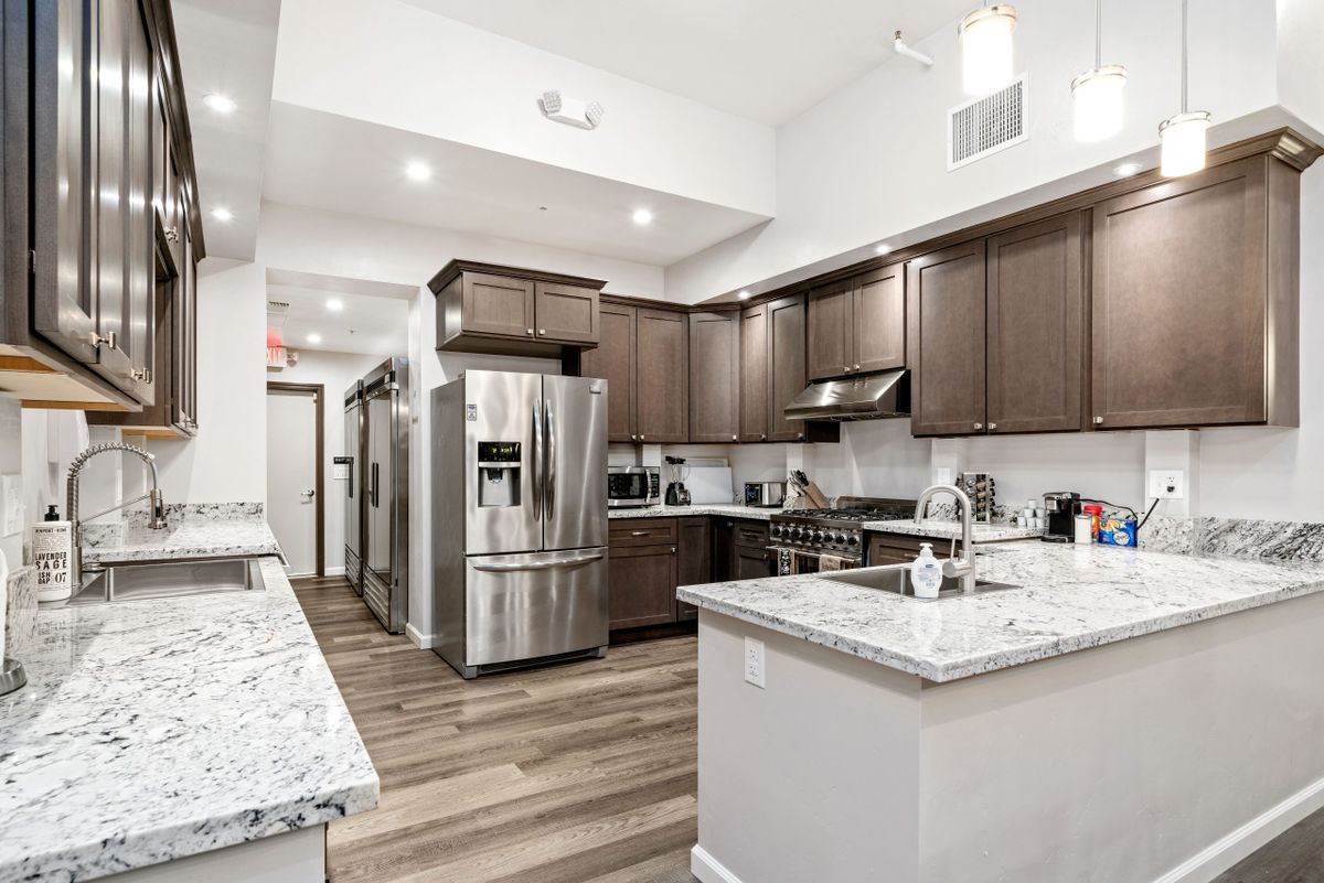 A spacious modern kitchen with stainless steel appliances, wooden flooring, and granite countertops.