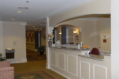 A quiet reception area with a front desk and hallway in a hotel.