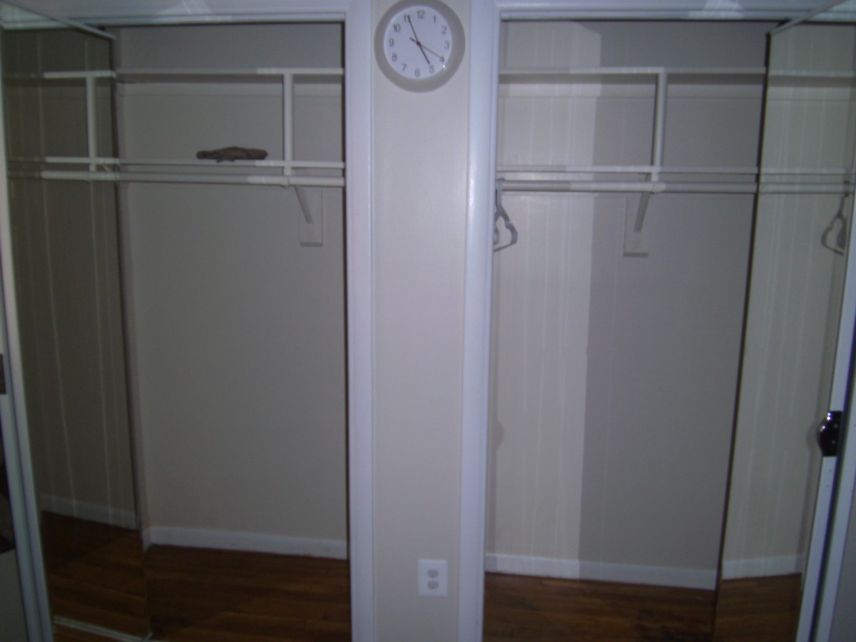 An empty closet with a wall clock mounted above the center divider.