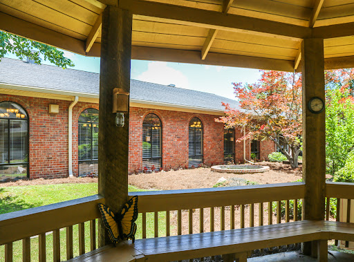 A peaceful view from the porch, showcasing a beautifully landscaped brick home.