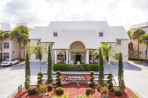 A large building with a grand entrance and well-manicured landscaping featuring palm trees.