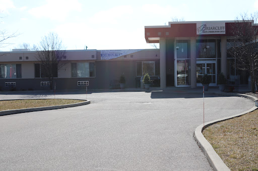 A view of a bank building with a driveway and parking area on a sunny day.