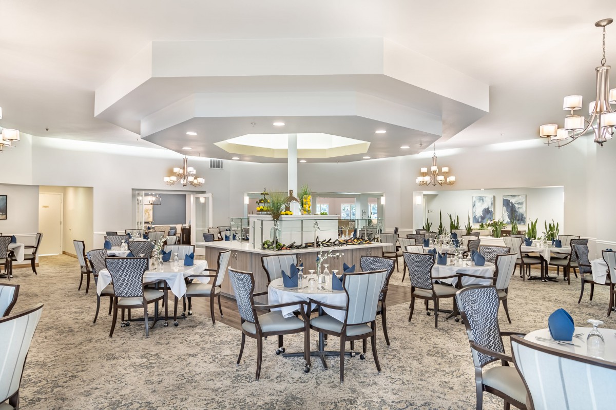 An elegant dining area with neatly arranged tables and chairs, featuring chandeliers and sophisticated decor.