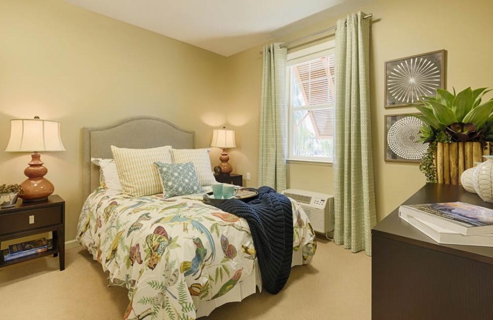 A cozy bedroom with a neatly made bed, soft pillows, and elegant curtains by the window.