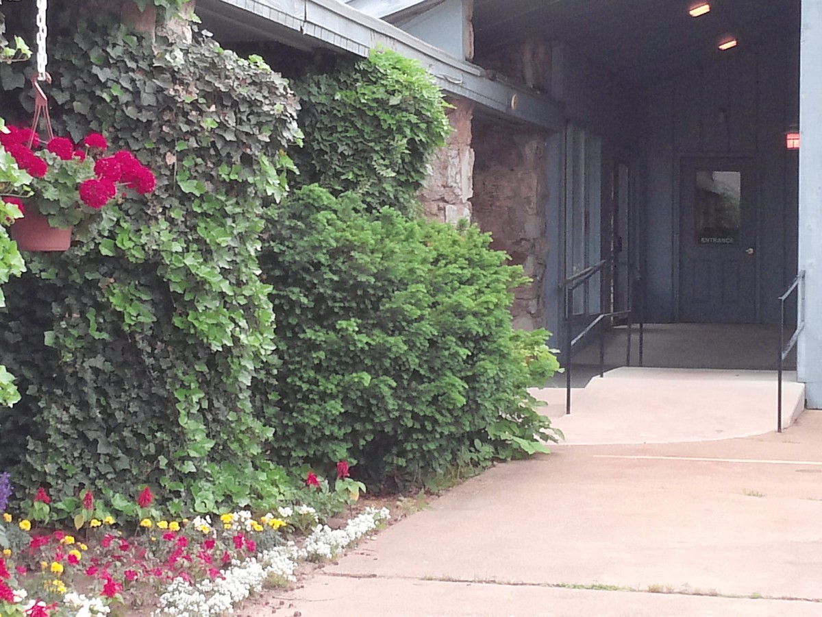 A scenic view of a building entrance adorned with lush greenery and colorful flowers.