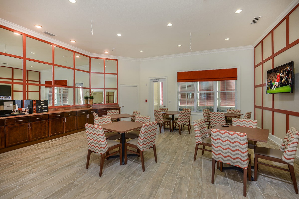 A modern dining area with multiple tables and chairs, featuring large windows and stylish decor.