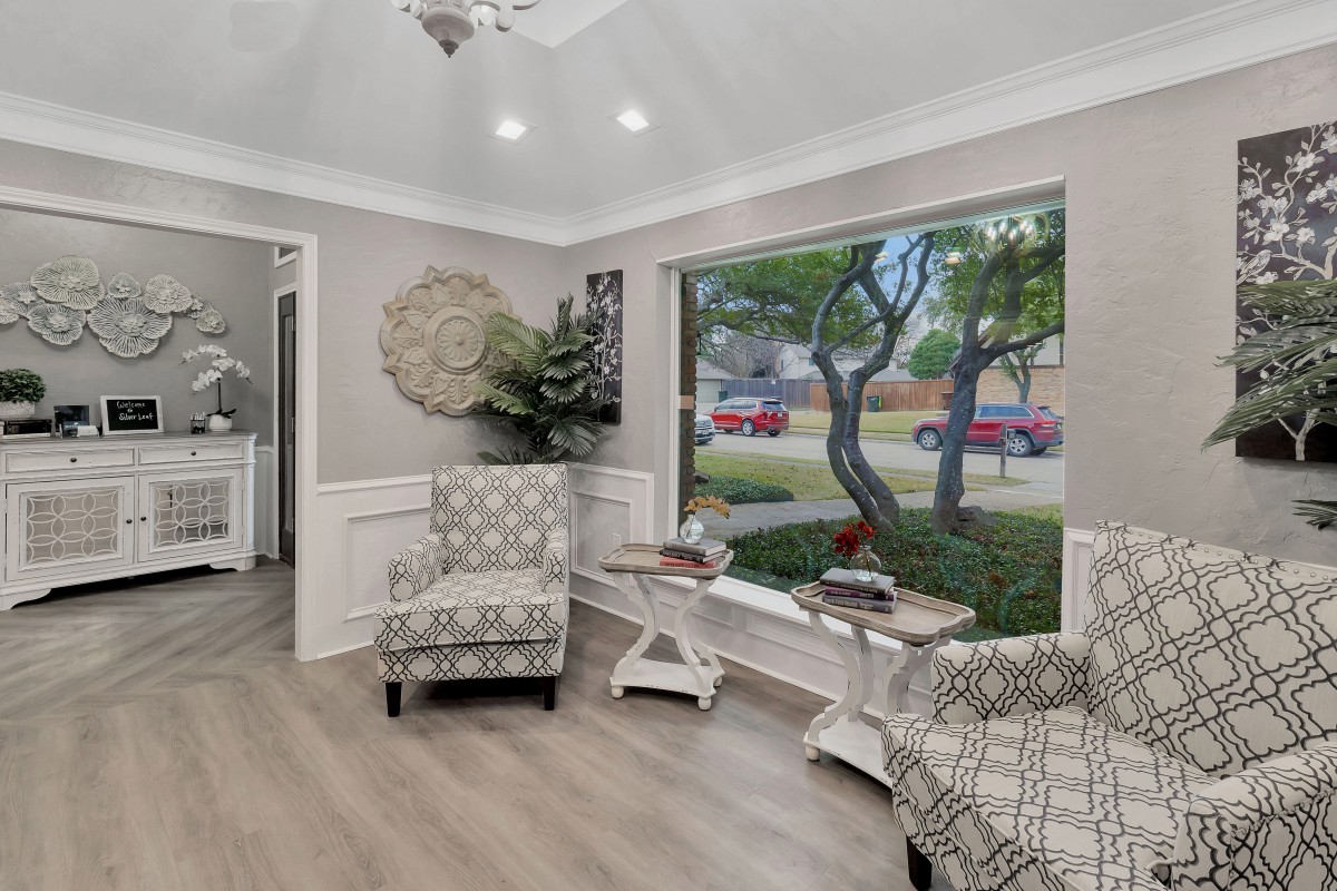 A modern living room with patterned chairs and a large window overlooking the street.