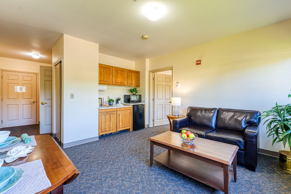 A cozy living room featuring a kitchenette, leather sofa, and coffee table.