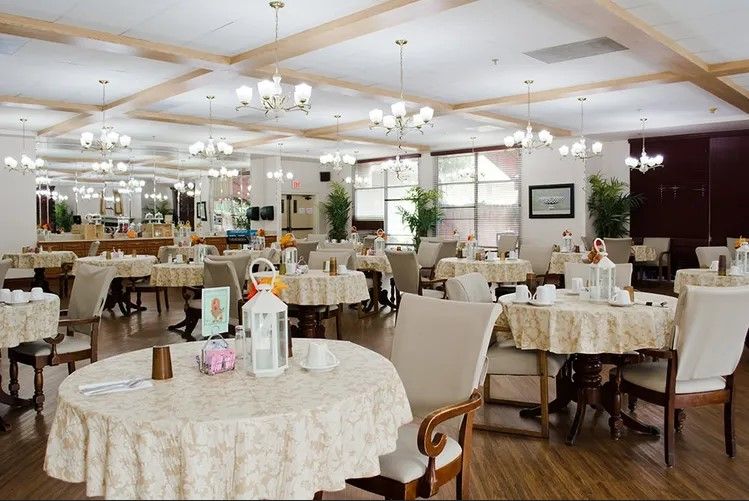 A well-lit dining room with elegantly set tables and chandeliers.